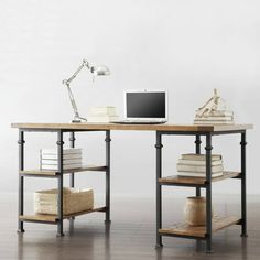 a computer desk with books and a laptop on it in front of a white wall