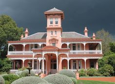 an old pink house with white balconies on the front