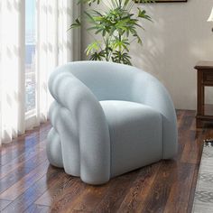 a blue chair sitting on top of a hard wood floor next to a plant in a living room