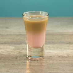 a glass filled with liquid sitting on top of a wooden table