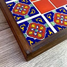 a wooden table topped with colorful tiles on top of it's sides and bottom