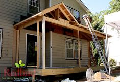 a house is being built with wood and siding on the front porch, while a ladder stands next to it