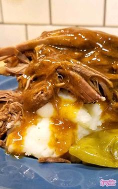 a blue plate topped with meat and potatoes covered in gravy