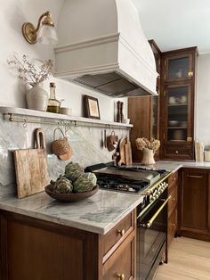 a kitchen with marble counter tops and wooden cabinets in the corner, along with hanging utensils