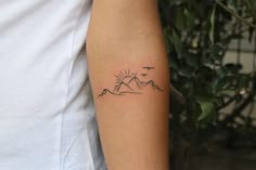 a person with a tattoo on their arm that has mountains and birds in the sky