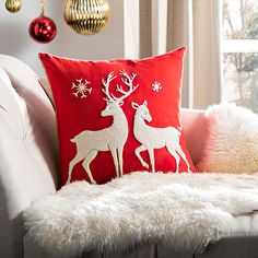 a christmas pillow sitting on top of a couch next to a white fur covered chair