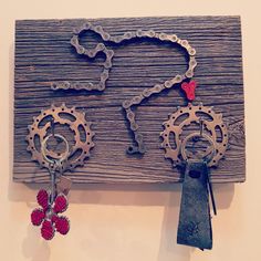 two key chains hanging on a wooden board with other items attached to it and some red flowers