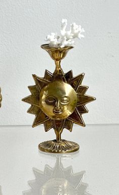 a golden vase sitting on top of a white table next to a gold candle holder