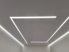 an empty room with some lights on the ceiling and white walls in front of it