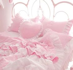 a pink bed with ruffled sheets and pillows