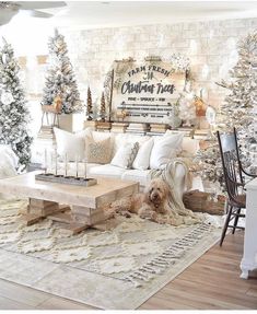 a living room decorated for christmas with white furniture and trees on the wall behind it