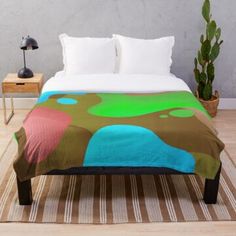 a bed sitting on top of a wooden floor next to a potted green plant