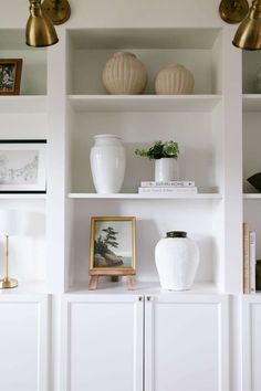 some white shelves with vases and pictures on them