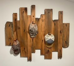 three sculptures on wooden planks mounted to the side of a wall, one with a vase and another with an animal's head