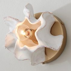 a light that is on the wall with a flower shaped lamp in front of it