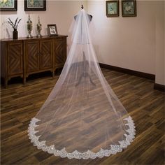 a wedding veil is hanging on a mannequin in a room with wood flooring