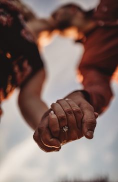 two people holding hands with the sky in the background