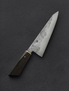 a large knife with a wooden handle on a black table top, next to it's blade