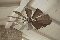 a ceiling fan with wooden blades hanging from it's center point in a living room