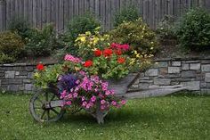 a wheelbarrow filled with colorful flowers sitting in the grass