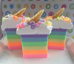 there are three pieces of cake with rainbow frosting on them and sprinkles