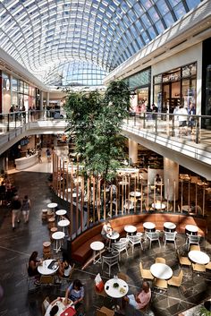 people are sitting at tables and eating in the atrium of a shopping mall with glass ceiling