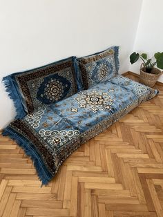 a couch that is sitting on the floor in front of a potted plant and rug