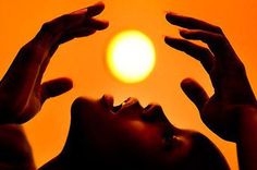 a woman looking up at the sun through her hands