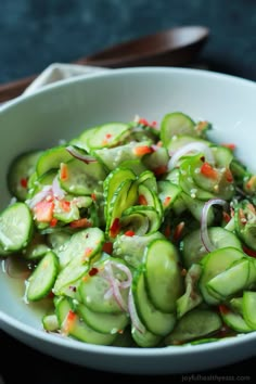 a white bowl filled with cucumbers and onions