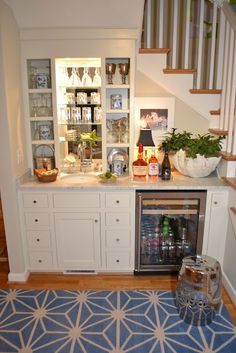 a small kitchen with white cabinets and blue rugs on the floor, under stairs