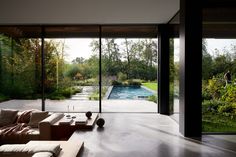 a living room with couches, tables and large glass doors leading to an outdoor swimming pool