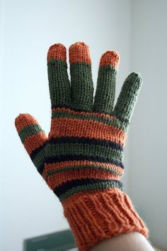 a hand wearing an orange and green knitted glove