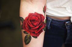 a woman's arm with a red rose tattoo on it