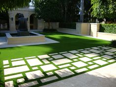 an outdoor area with artificial grass and stepping stones in the center, surrounded by greenery