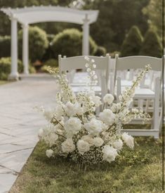 an outdoor ceremony set up with white chairs and flowers