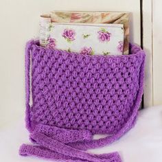 a purple crocheted purse sitting on top of a white table next to a door