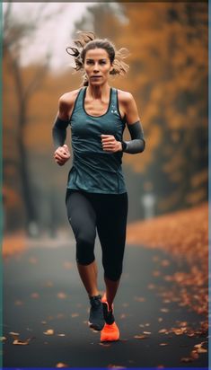 a woman running down a road with trees in the background and leaves on the ground