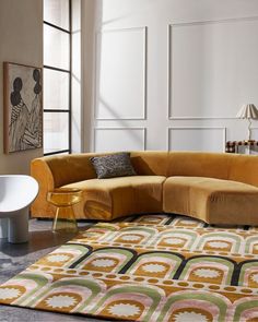 a living room with a large sectional couch and colorful rugs on the floor in front of windows