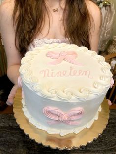 a woman holding a white and pink cake