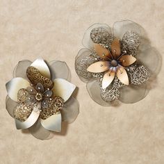 two metal flowers on top of a beige wall next to each other with filigrees