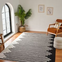 a black and white rug sitting on top of a wooden floor next to a window