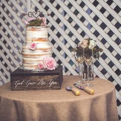 a wedding cake sitting on top of a table next to two vases filled with flowers