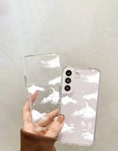 a person holding up a clear phone case with clouds in the sky on it,