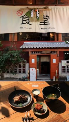 a table topped with plates of food on top of a wooden table next to a building