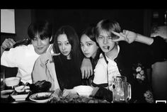 black and white photograph of four young people at a table with food in front of them