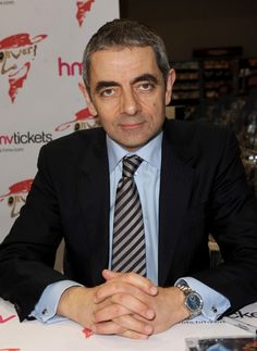 a man in a suit and tie sitting at a table with his hands folded out