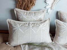 three pillows on a bed with feathers hanging from the headboard and one is made out of linen