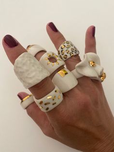 a woman's hand with five different rings on it, all decorated in gold and white