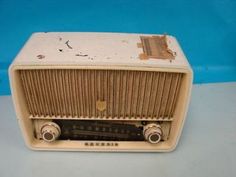 an old radio sitting on top of a white table next to a blue wall in the background