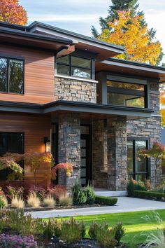 a modern house with stone and wood accents in the front yard, surrounded by colorful trees